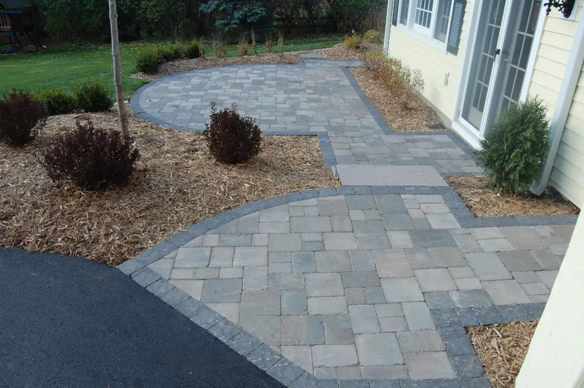 Paver patio connected to a home, walkway, and surrounding planting beds