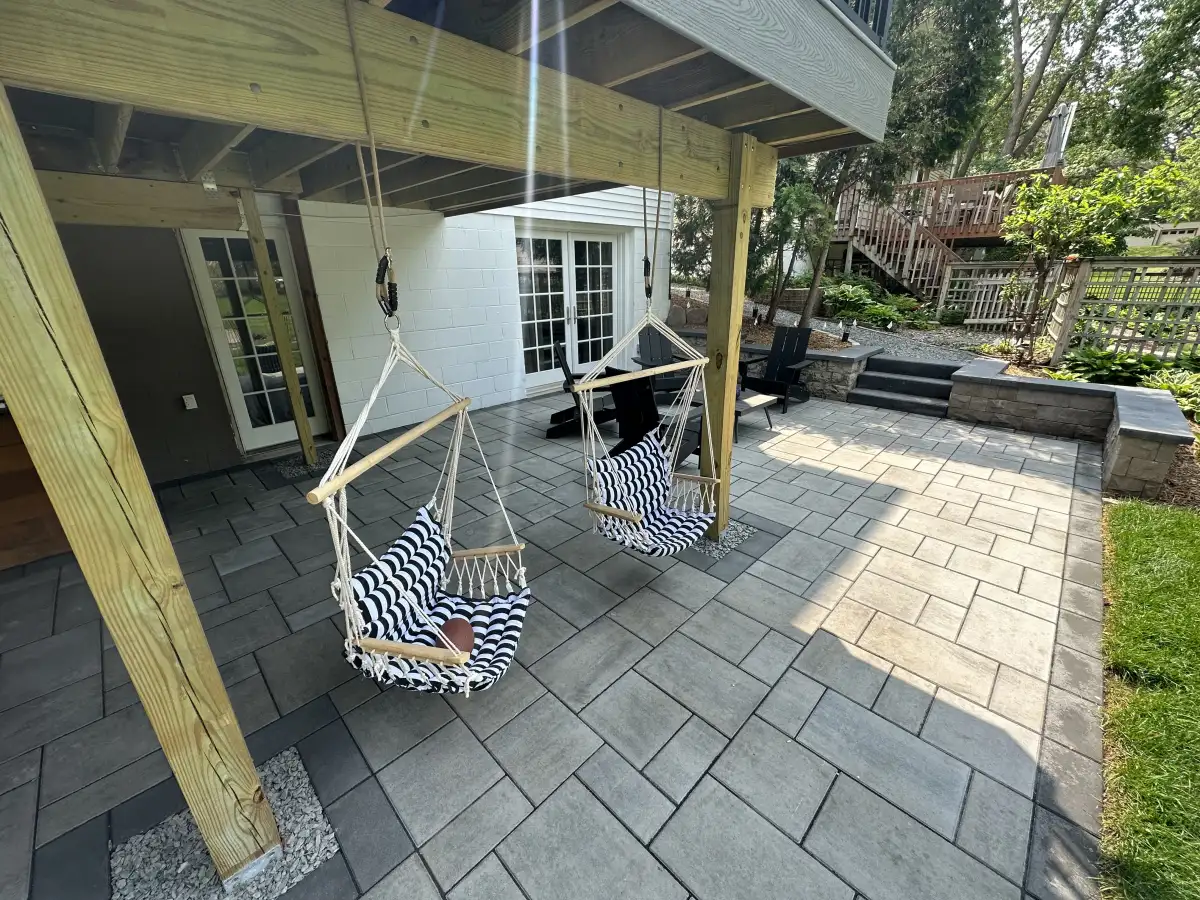 Paver patio with covered seating, steps, walls, and yard connections